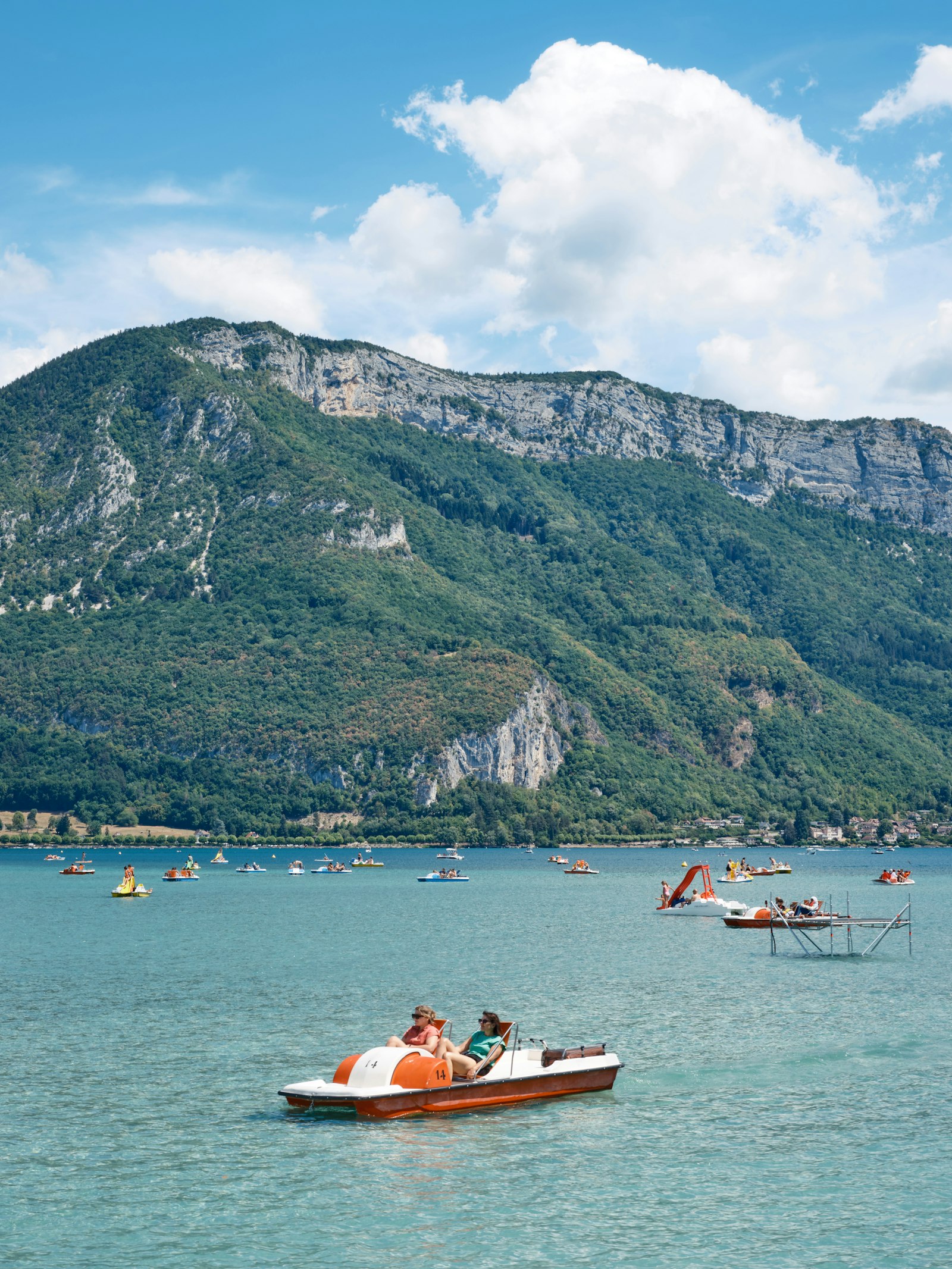 A small boat on Lake Annecy with mountains in the background