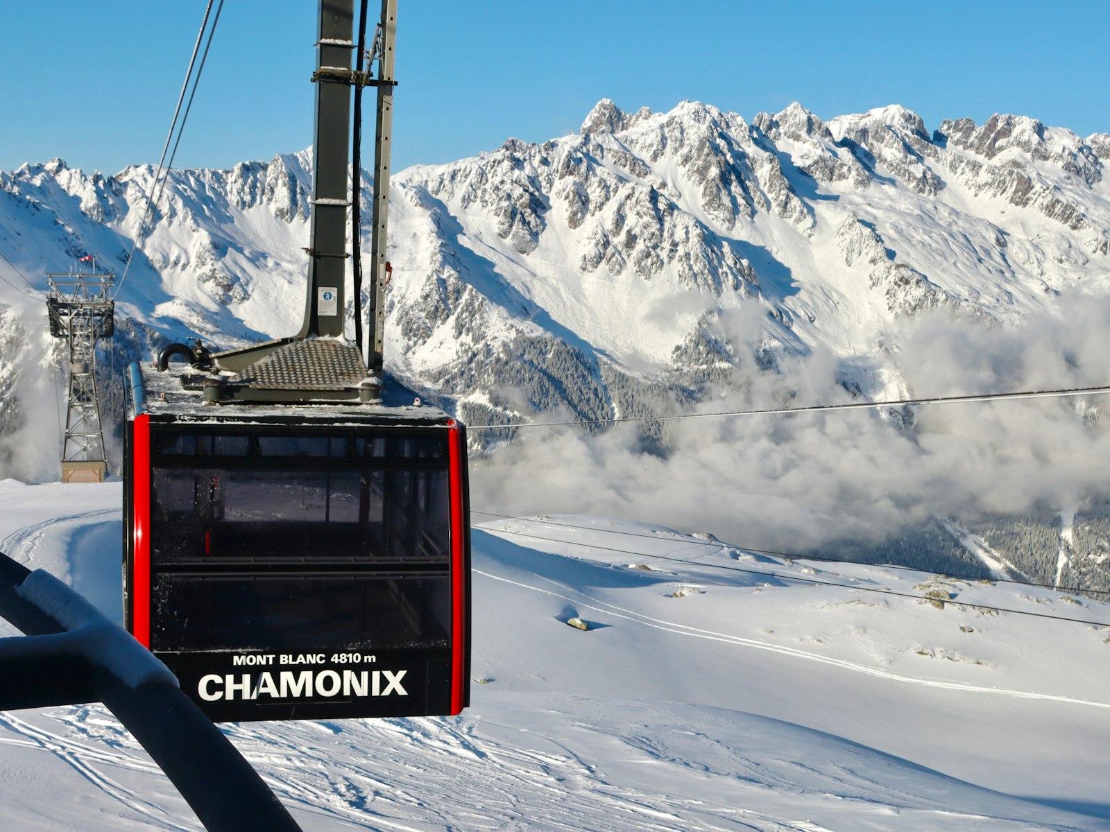 A cable car ascending above snow-covered terrain near Chamonix