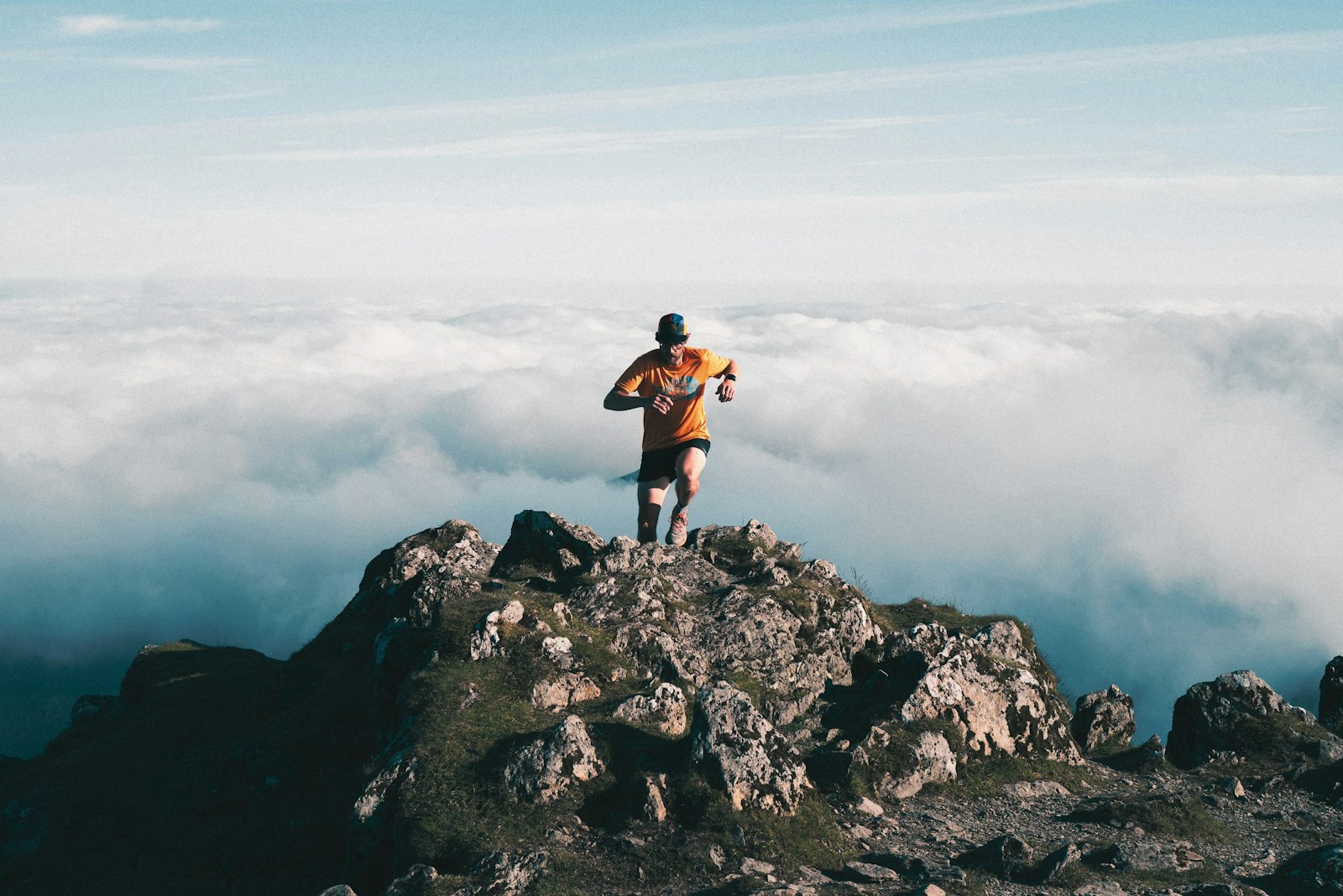 A trail runner on a rocky mountain peak above the clouds